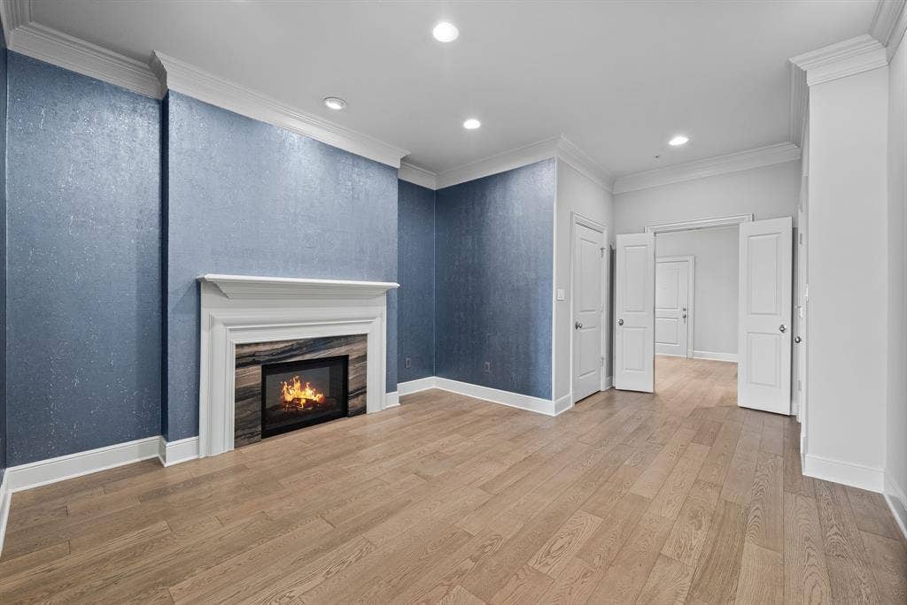 4240 Prescott Avenue, #8B, Dallas, TX 75219 Spacious room featuring a fireplace with a white mantel and stone surround, wood-finish flooring, recessed lighting, and crown molding