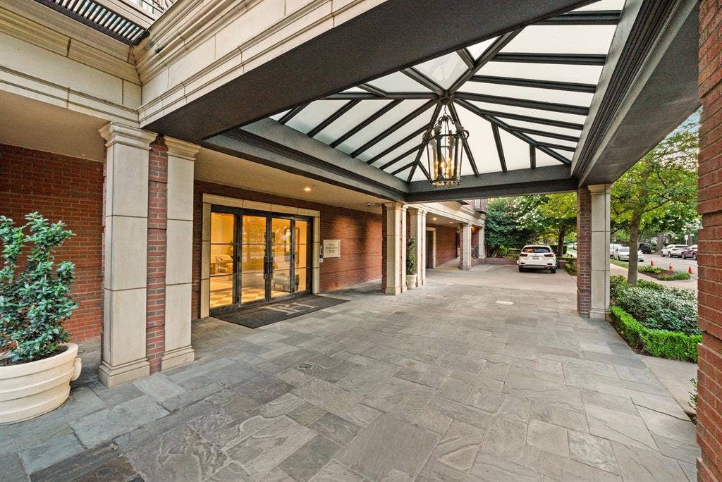 4240 Prescott Avenue, #8B, Dallas, TX 75219 Elegant porte-cochere entrance featuring a glass and metal canopy, stone tile flooring, and a large hanging lantern