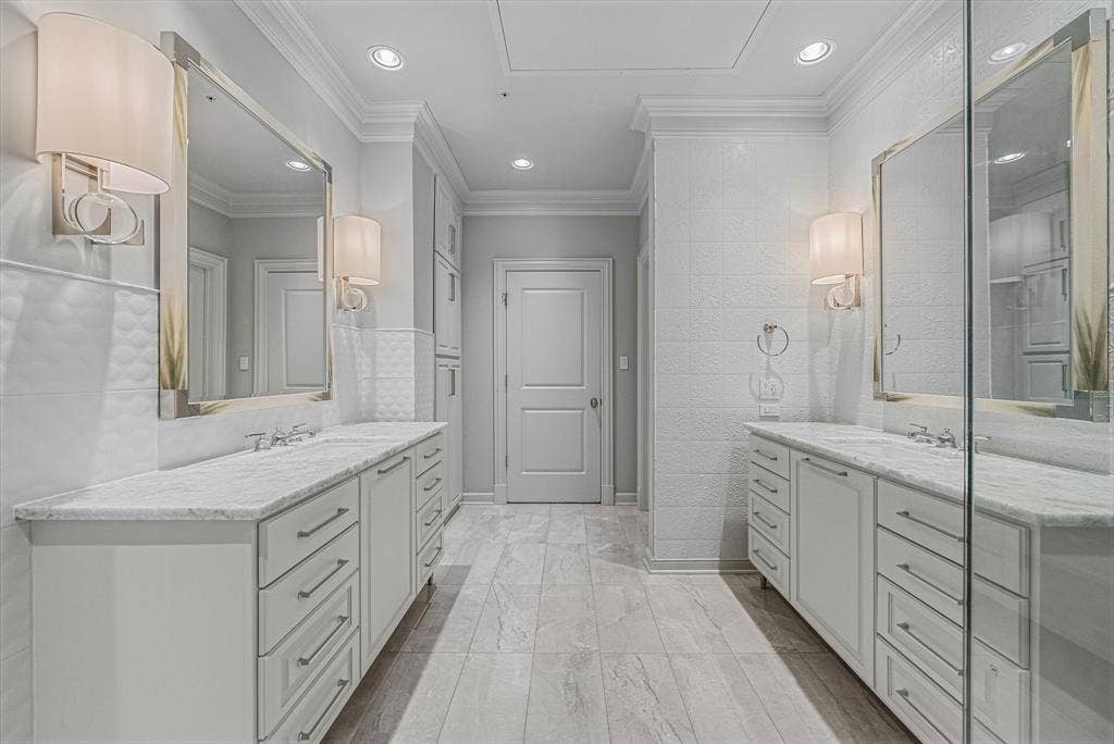 4240 Prescott Avenue, #8B, Dallas, TX 75219 Spacious bathroom featuring dual vanities with stone countertops, ample cabinet and drawer storage, framed mirrors, and wall sconces