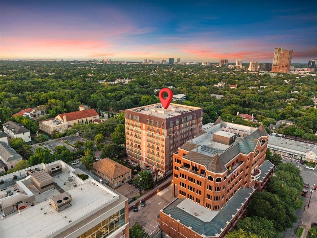 4240 Prescott Avenue, #8B, Dallas, TX 75219 Mid-rise building featuring a red brick facade, a prominent mansard roof, and individual private balconies