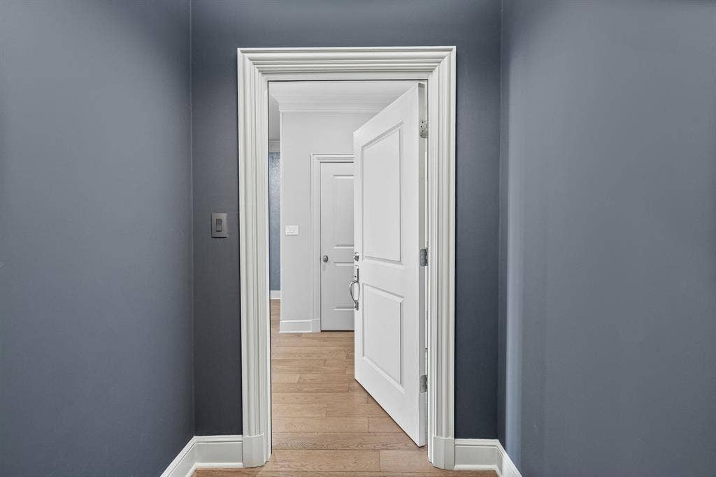 4240 Prescott Avenue, #8B, Dallas, TX 75219 Hallway featuring a neutral wall color, white trim, and wood-finish flooring extending into the adjoining room