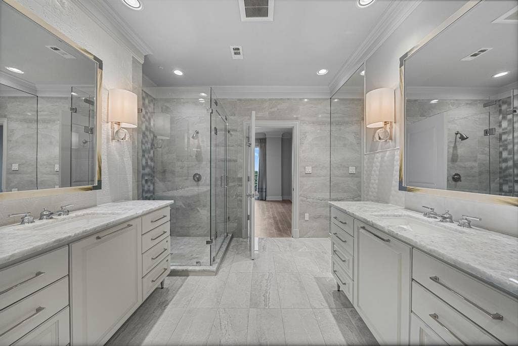 4240 Prescott Avenue, #8B, Dallas, TX 75219 Spacious bathroom featuring dual vanities with integrated sinks, framed mirrors, and wall sconces