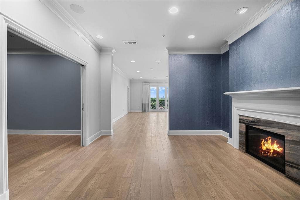 4240 Prescott Avenue, #8B, Dallas, TX 75219 Spacious interior featuring wood-finish flooring, a contemporary fireplace with stone surround and white mantel, recessed lighting, and a textured accent wall
