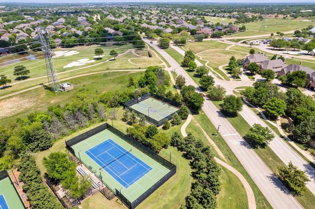 Aerial perspective showcasing community amenities including tennis courts, a basketball court, and walking paths