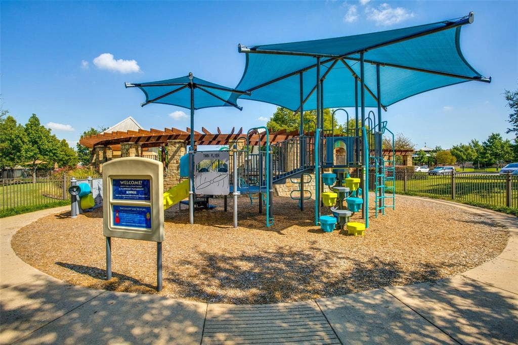 Playground area featuring a multi-level structure with blue shade coverings, slides, and climbing elements