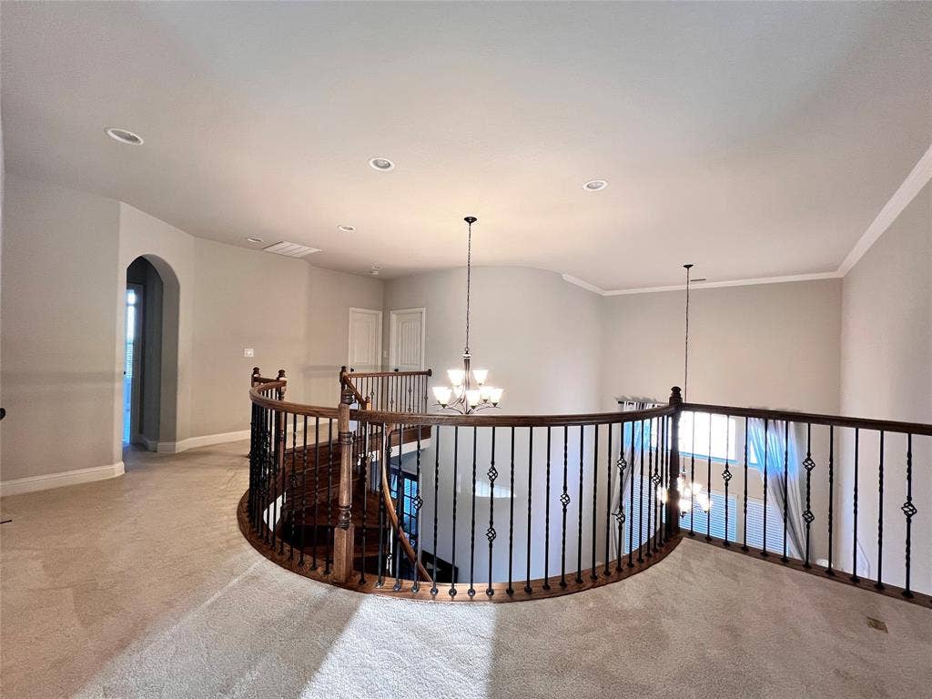 Upper-level landing featuring a curved overlook with wrought iron balusters and a wood-finish handrail