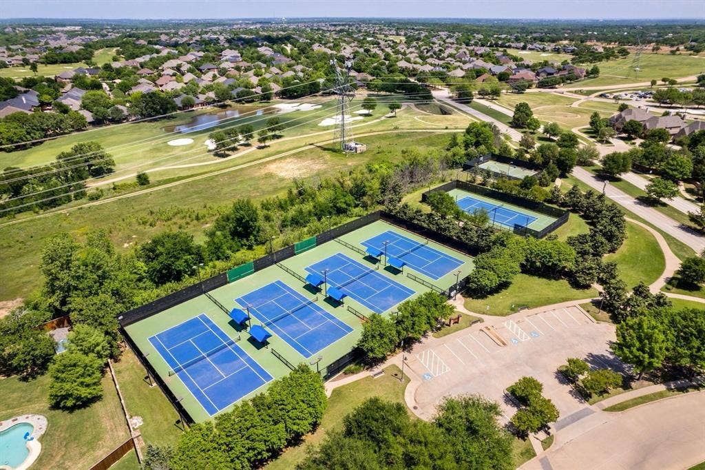 Community tennis courts and a golf course green, surrounded by residential properties and mature trees