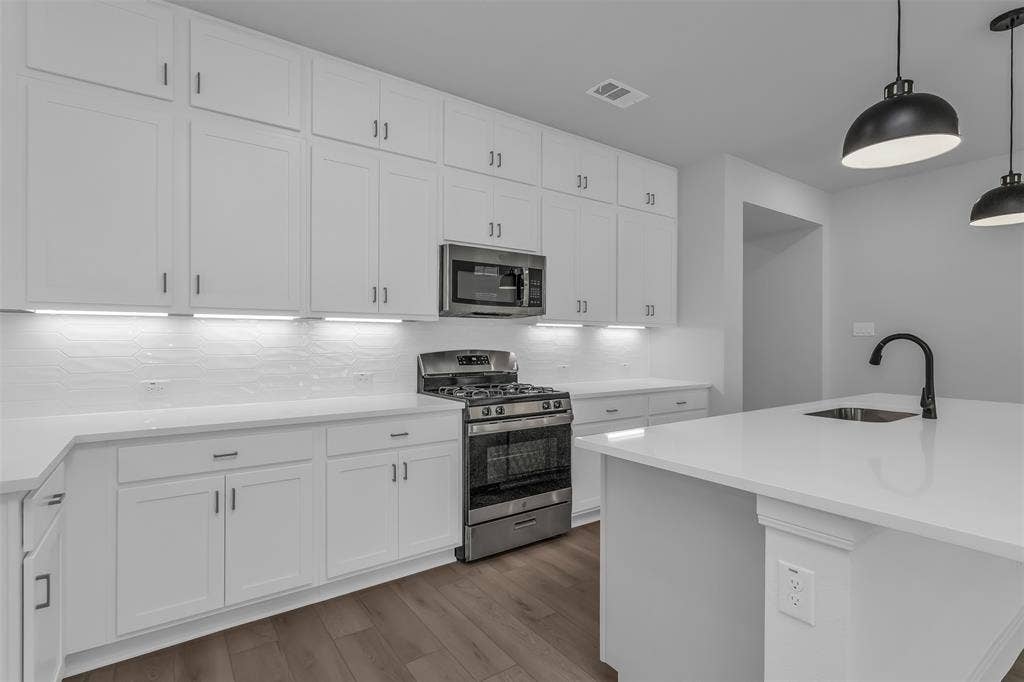 1031 Rylan Street, Midlothian, TX 76065 Modern kitchen featuring white shaker cabinetry, stainless steel appliances, a gas range, white countertops, and wood-finish flooring