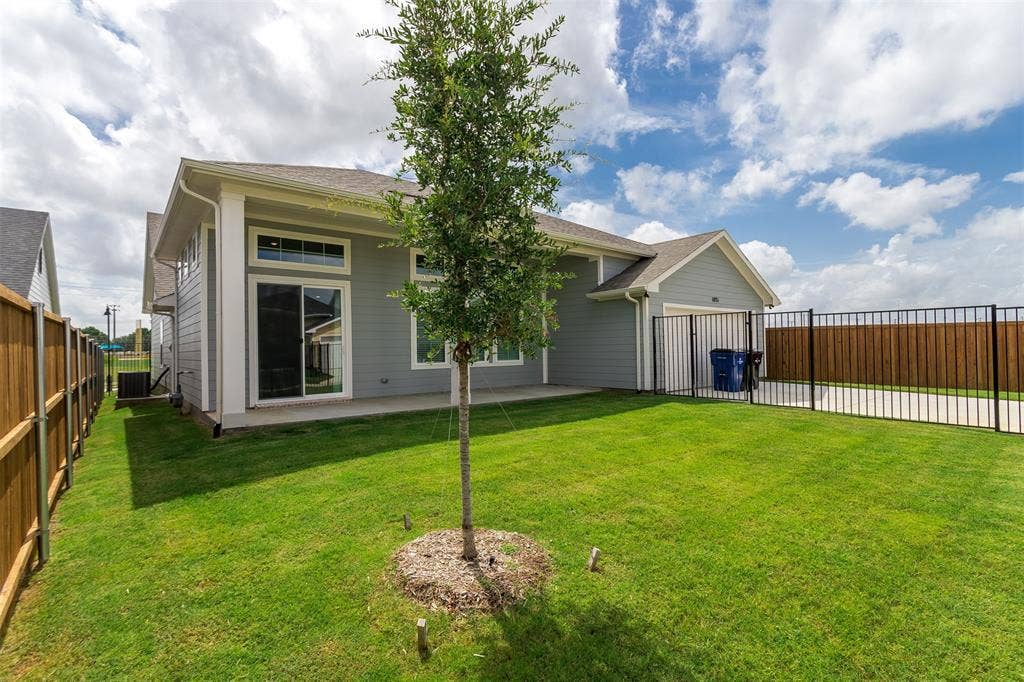 1031 Rylan Street, Midlothian, TX 76065 Expansive rear yard featuring a manicured lawn, a young tree, and a concrete patio