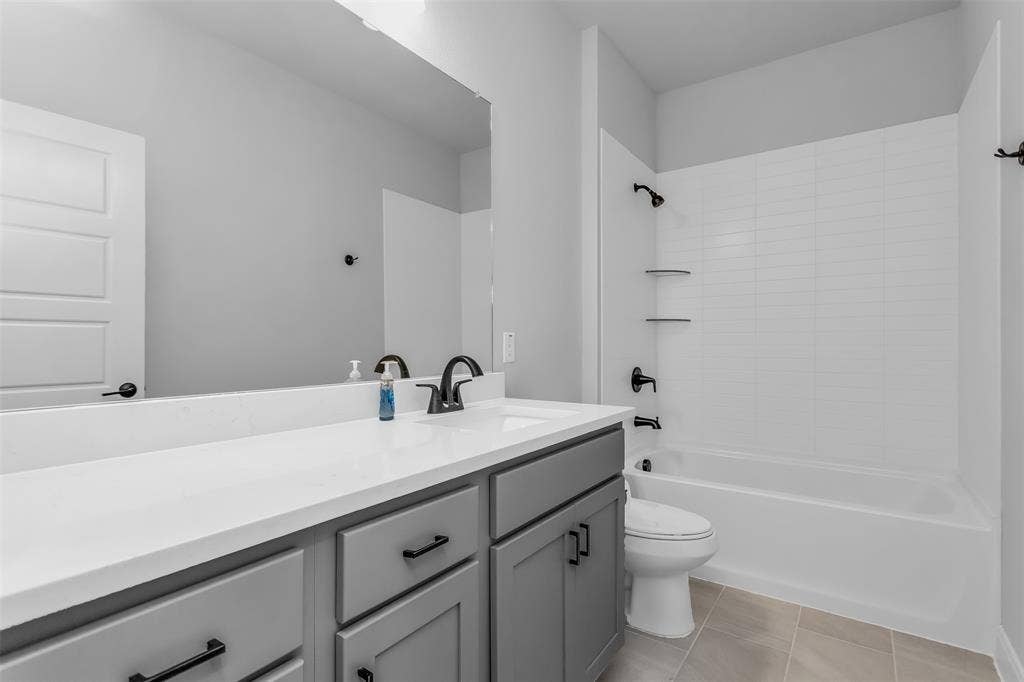 1031 Rylan Street, Midlothian, TX 76065 Contemporary bathroom featuring a spacious vanity with shaker-style cabinetry, a solid surface countertop with an integrated sink, and matte black fixtures