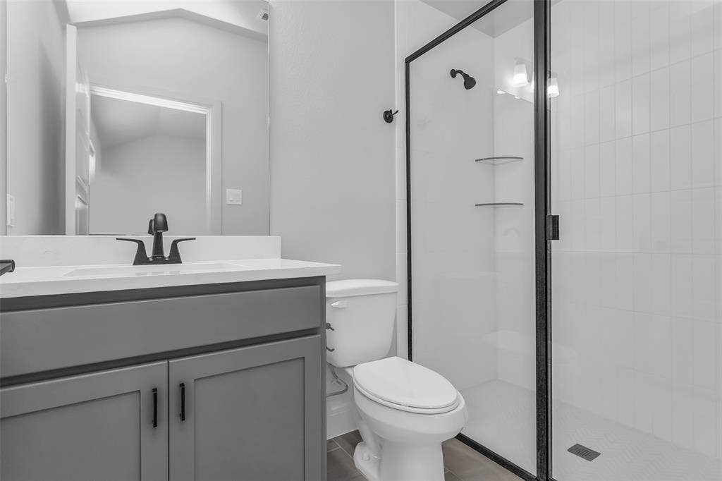 1031 Rylan Street, Midlothian, TX 76065 Bathroom featuring a grey vanity with a white countertop, matte black fixtures, a frameless mirror, and a glass-enclosed shower with white subway tile