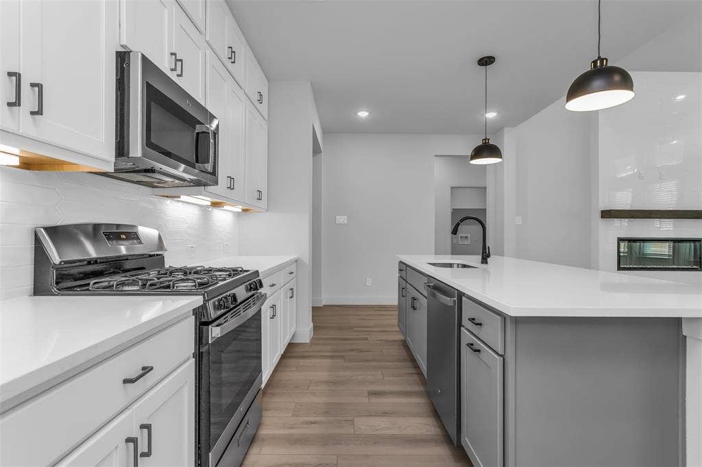 1031 Rylan Street, Midlothian, TX 76065 Modern kitchen featuring white shaker cabinetry, stainless steel appliances, and wood-finish flooring