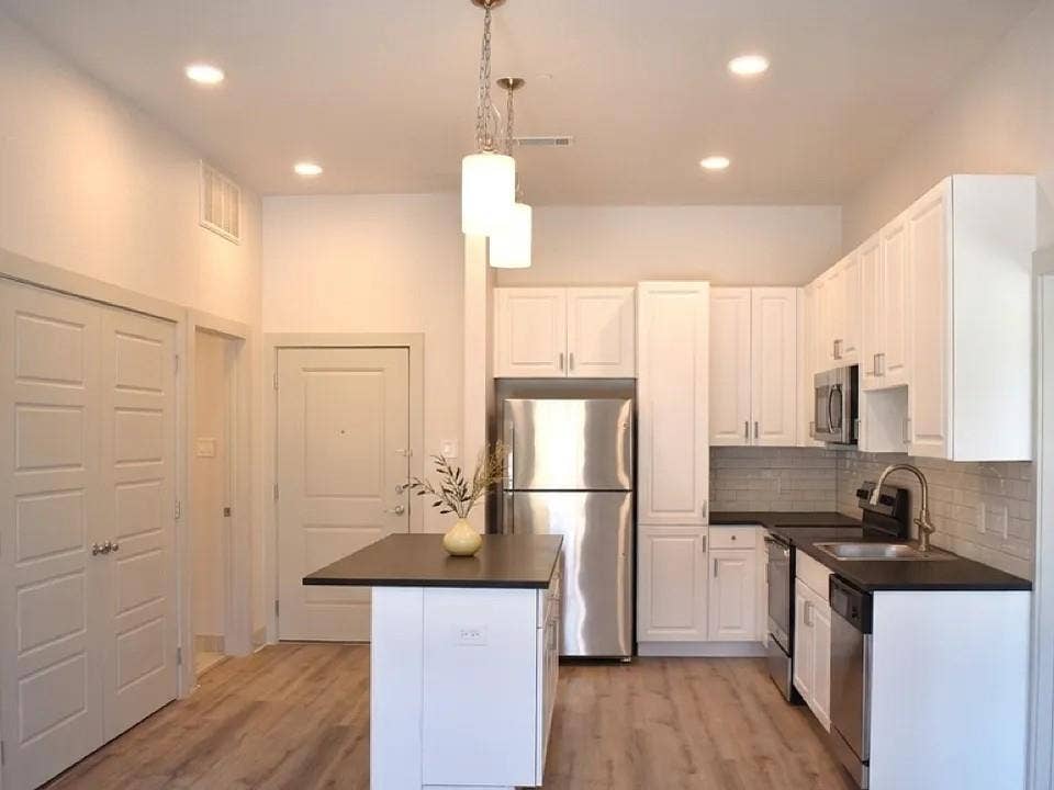 1514 E 15th Street, #10, Plano, TX 75074 Kitchen featuring white shaker cabinetry, stainless steel appliances, dark countertops, a subway tile backsplash, and wood-finish flooring