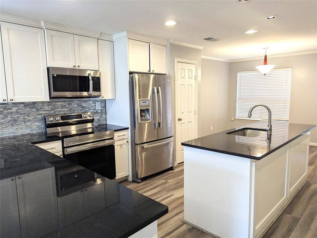 509 Pine Trail Drive, Allen, TX 75002 Kitchen featuring white cabinetry, dark countertops, stainless steel appliances, a stone backsplash, and wood-finish flooring