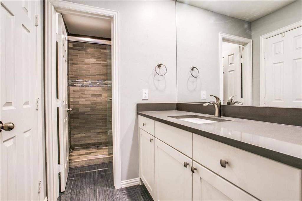509 Pine Trail Drive, Allen, TX 75002 Bathroom vanity with a gray countertop, an undermount sink, and a large wall-mounted mirror