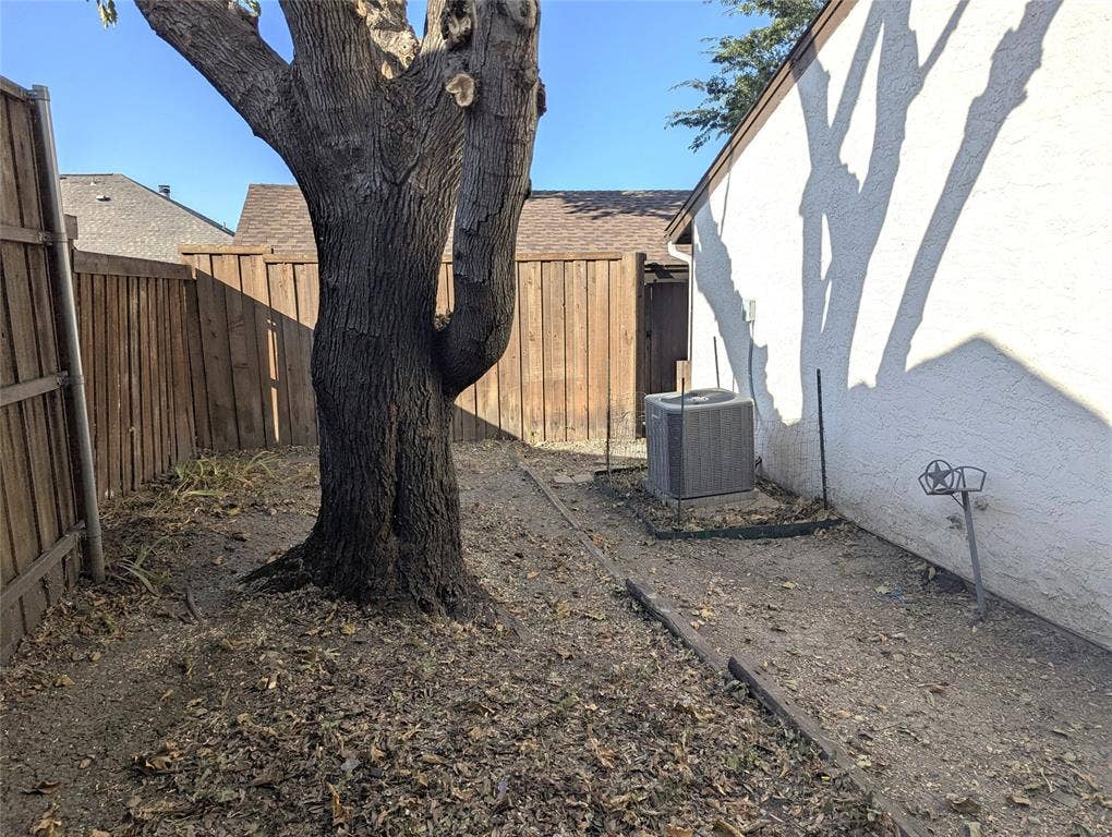 509 Pine Trail Drive, Allen, TX 75002 Mature tree with a textured trunk, wood fencing, and a stucco exterior