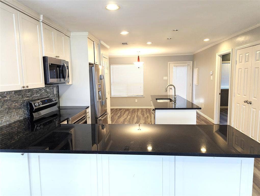 509 Pine Trail Drive, Allen, TX 75002 Kitchen featuring white cabinetry, stainless steel appliances, dark countertops, a stone-finish backsplash, and wood-finish flooring