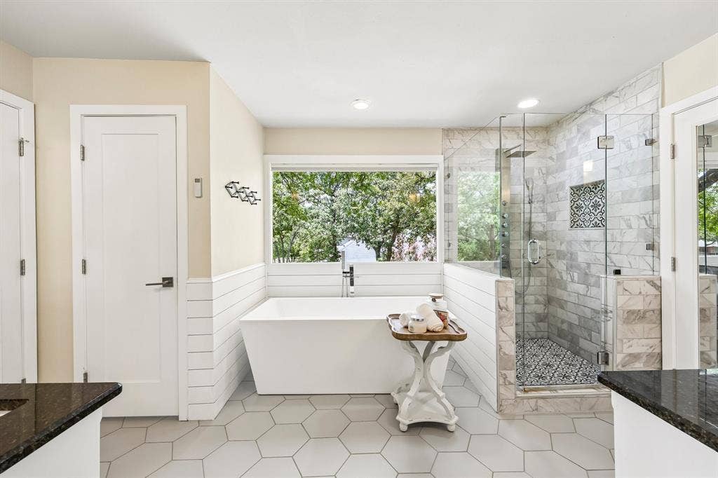 711 Bandit Trail, Keller, TX 76248 Freestanding soaking tub, walk-in shower with glass enclosure, white hexagon floor tiling, dark countertop, and shiplap wall paneling