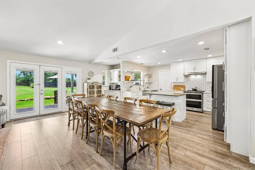 711 Bandit Trail, Keller, TX 76248 White shaker cabinetry with stainless steel appliances, central island with seating, subway tile backsplash, recessed lighting, and wood-finish flooring