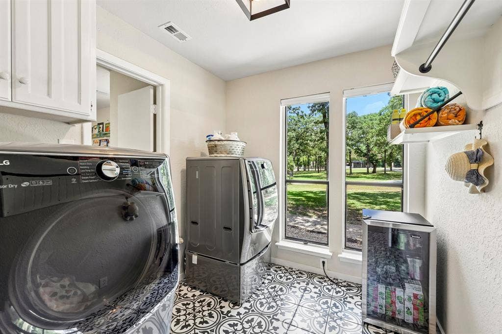 711 Bandit Trail, Keller, TX 76248 Laundry space featuring patterned floor tiles, white shaker-style cabinetry, and dual windows