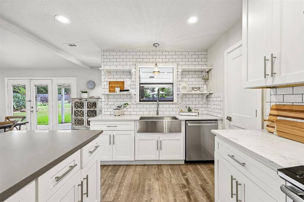 711 Bandit Trail, Keller, TX 76248 White cabinetry, subway tile backsplash, stainless steel appliances, stainless steel farmhouse sink, and wood-finish flooring