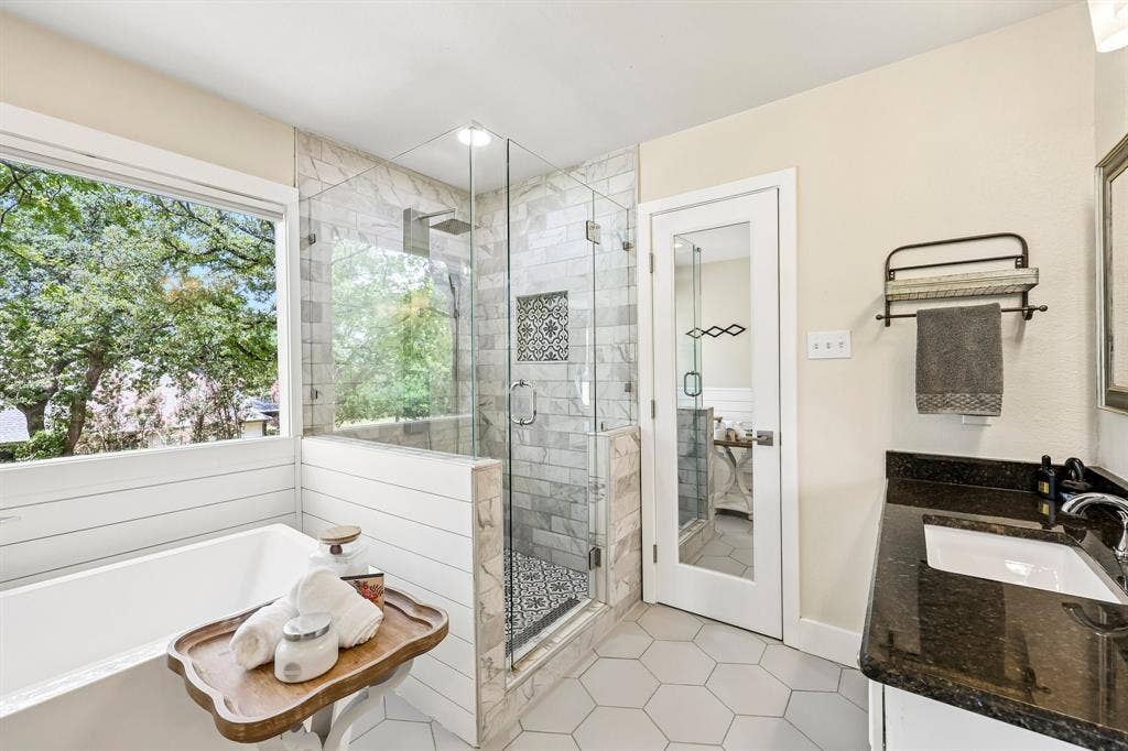 711 Bandit Trail, Keller, TX 76248 Freestanding soaking tub, glass-enclosed shower with tiled surround, dual shower heads, hexagonal floor tiles, and a vanity with a dark countertop and undermount sink