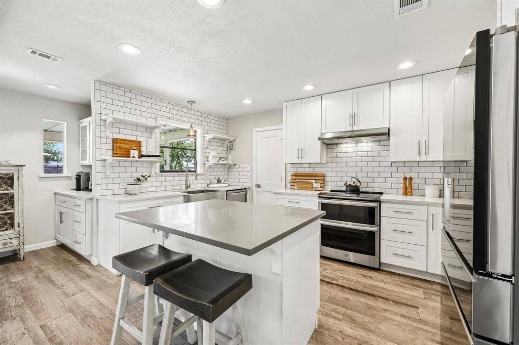 711 Bandit Trail, Keller, TX 76248 Kitchen featuring a central island with a solid surface countertop, white cabinetry, wood-finish flooring, subway tile backsplash, and stainless steel appliances