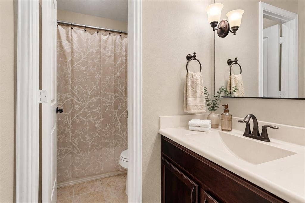 Bathroom vanity featuring a single basin, bronze-finish faucet, and coordinating wall-mounted light fixture