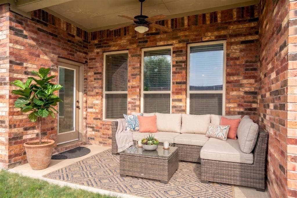Covered patio featuring brick exterior walls and a ceiling fan