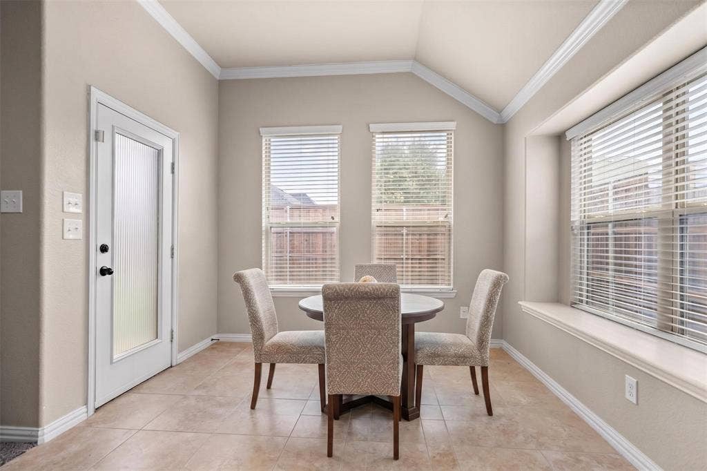 Breakfast nook featuring vaulted ceiling with crown molding, transom windows, and tile flooring