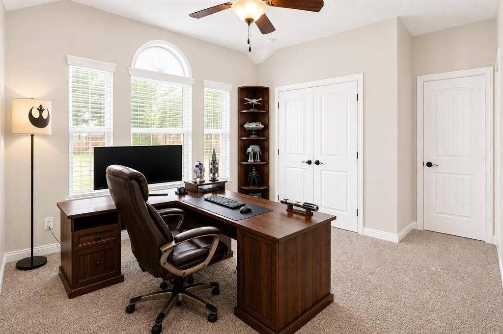 Bright room featuring vaulted ceilings, a ceiling fan, arched transom window, and two paneled interior doors