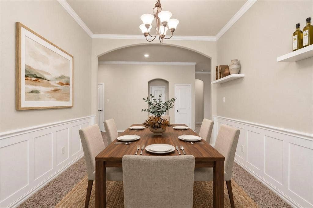 Dining area featuring wainscoting, crown molding, arched doorways, and a chandelier with glass shades