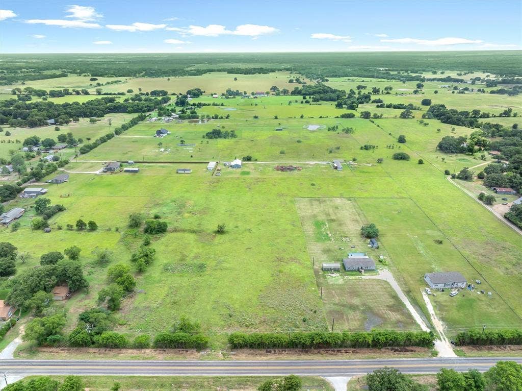 Lot 3R W. Cedar PKWY, Kemp, TX 75143 Expansive aerial property showcasing a vast green landscape with scattered trees, a paved road spanning the foreground, and residential structures throughout the distant fields