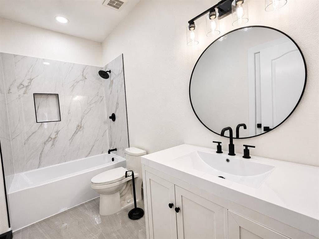 1706 Fairhaven Drive, Mansfield, TX 76063 Bathroom featuring a white vanity with integrated sink, black fixtures, and a circular framed mirror