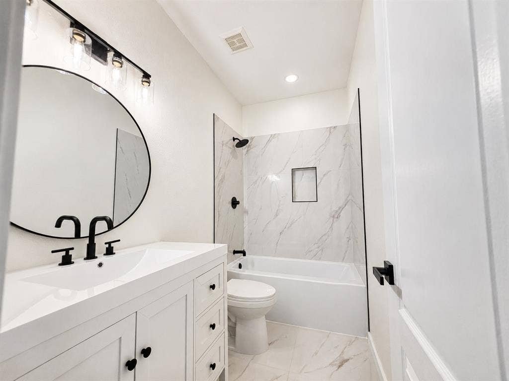 1706 Fairhaven Drive, Mansfield, TX 76063 Bathroom featuring a white vanity with integrated sink, matte black fixtures, and a circular framed mirror
