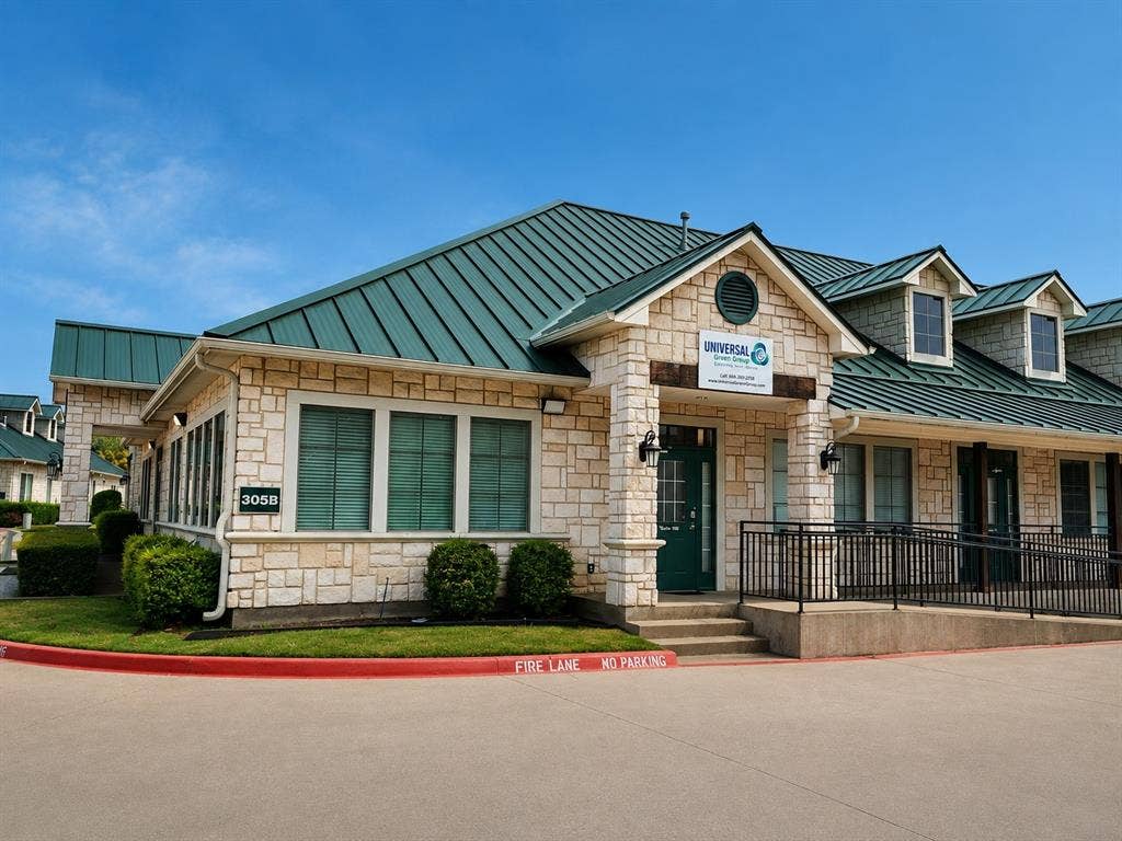 305 W Spring Creek Parkway, #5A, Plano, TX 75023 Stone-clad building featuring a dark green metal roof, multiple dormer windows, and a prominent entry porch