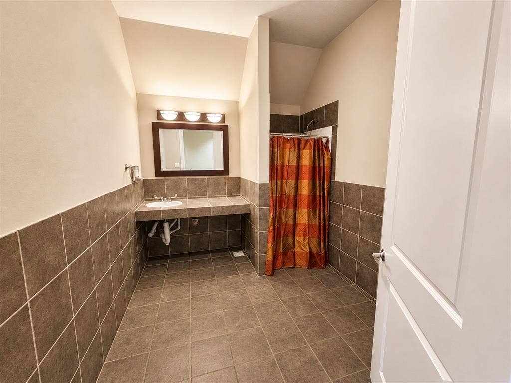 305 W Spring Creek Parkway, #5A, Plano, TX 75023 Spacious bathroom featuring large format floor tiles, coordinating wainscoting, and a single vanity with an integrated sink