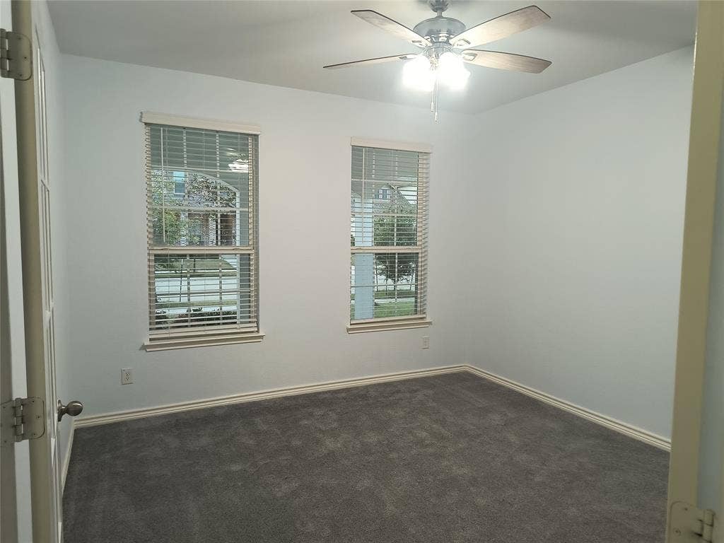 Room featuring two windows with horizontal blinds, neutral wall paint, and gray carpet flooring