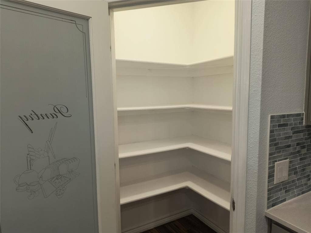Walk-in pantry featuring extensive corner shelving