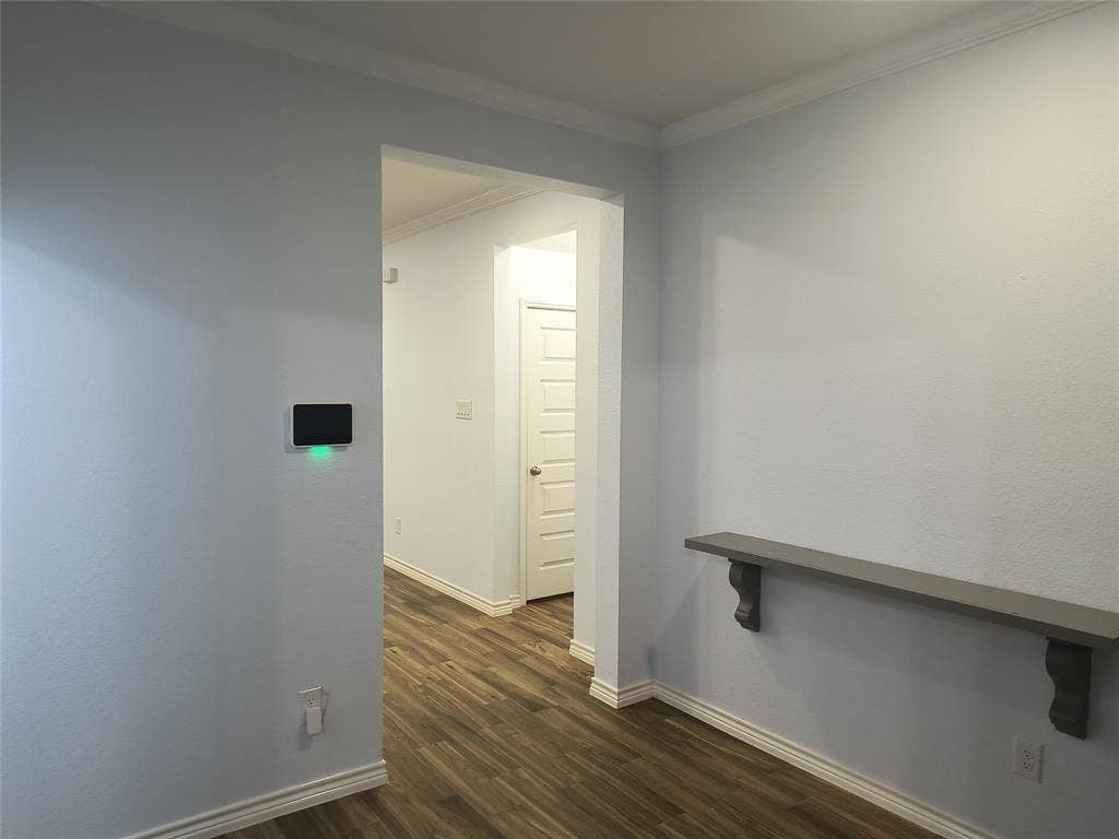 Interior hallway with wood-finish flooring, white baseboards, and crown molding