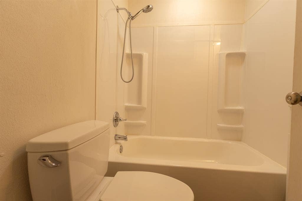 613 N 23rd Street, #15, Waco, TX 76707 White bathtub and shower combination featuring a chrome shower head and faucet