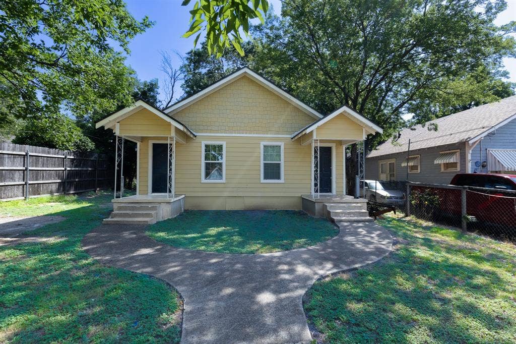 613 N 23rd Street, #15, Waco, TX 76707 Duplex property featuring a light yellow exterior with white trim, two separate entryways with covered porches, and a shared curved concrete walkway