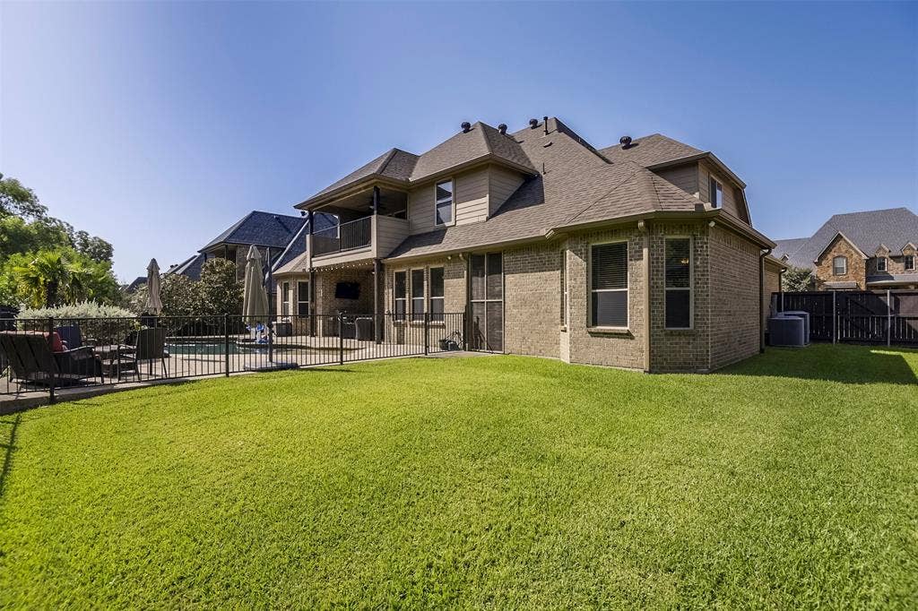 Expansive backyard featuring a large green lawn, a fenced swimming pool, and an outdoor patio area