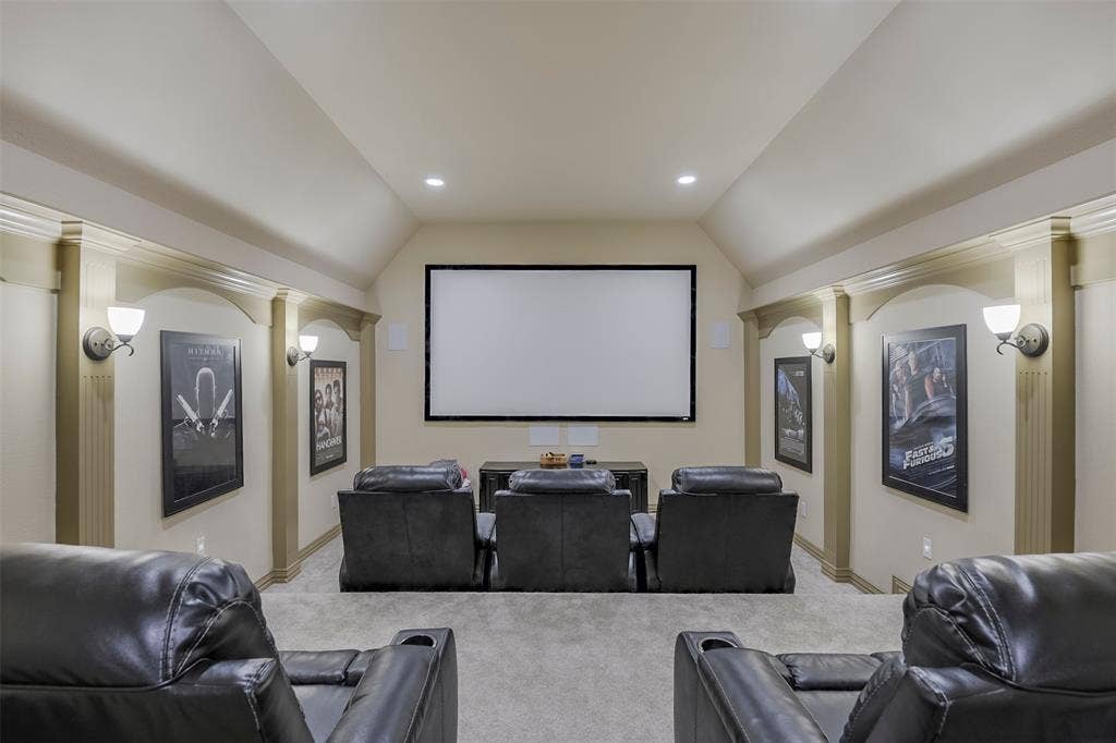 Dedicated media room featuring a large projection screen, recessed lighting, and wall sconces