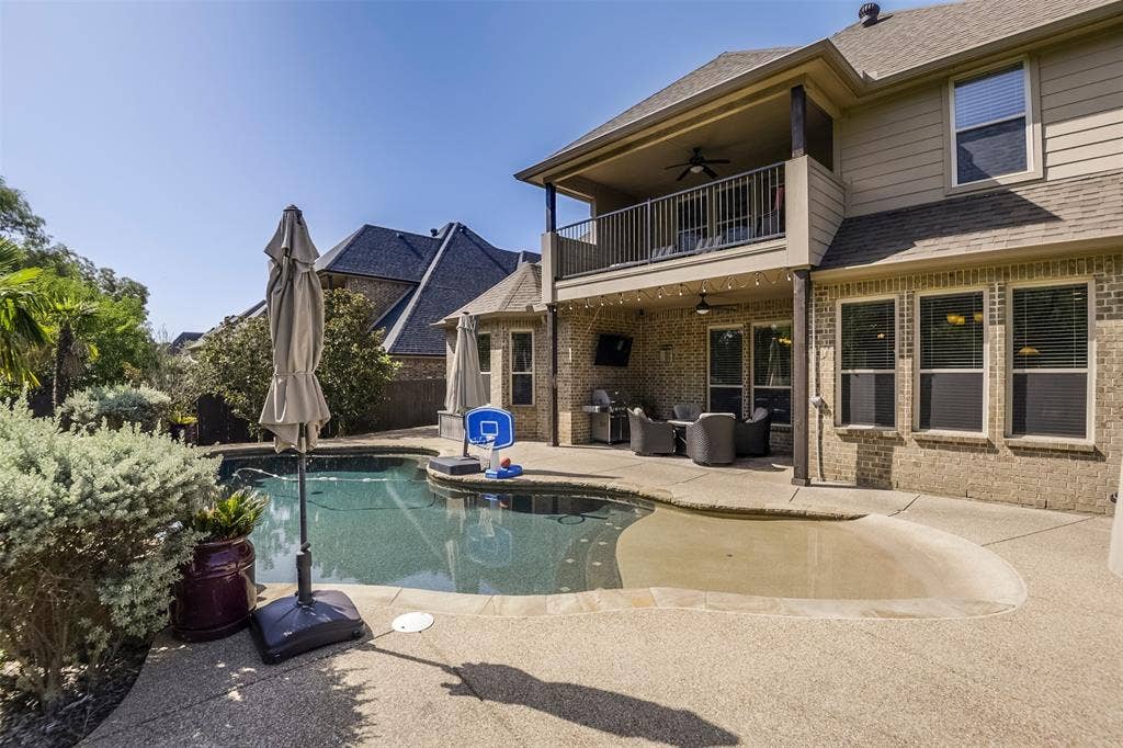 Outdoor oasis featuring zero entry swimming pool, expansive concrete decking, and lush perimeter landscaping