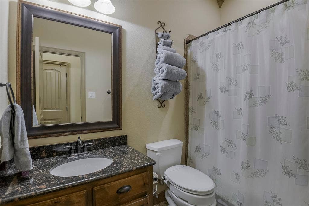 Bathroom featuring a wood-finish vanity with a granite countertop and an undermount sink