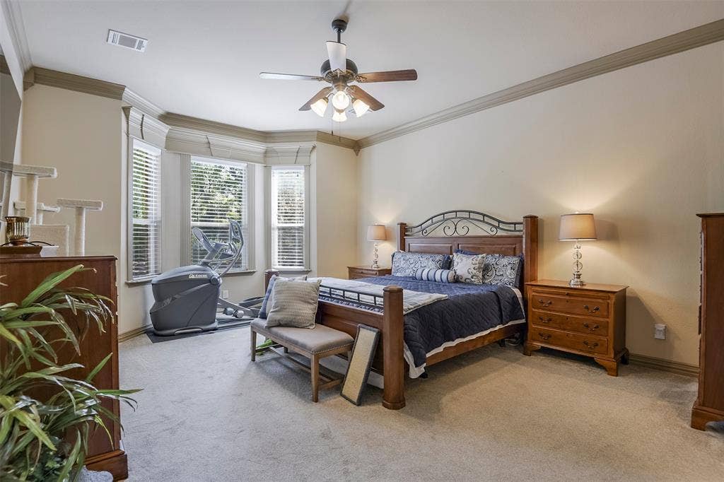 Spacious room featuring a bay window with multiple paneled windows, crown molding, and a ceiling fan