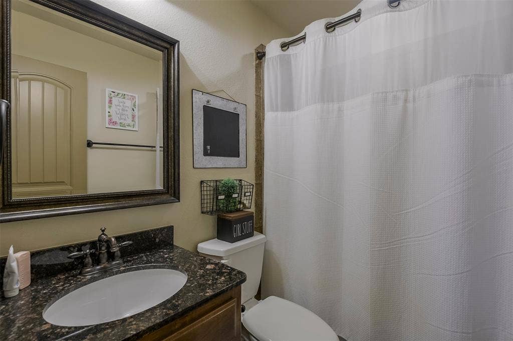 Bathroom featuring a vanity with a dark granite countertop, an undermount sink, and an oil-rubbed bronze faucet