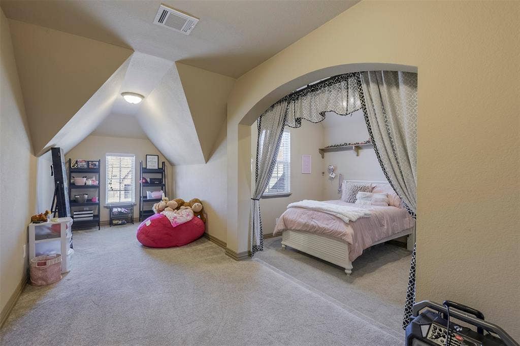 Carpeted room featuring an arched doorway, sloped ceilings, and a window with blinds