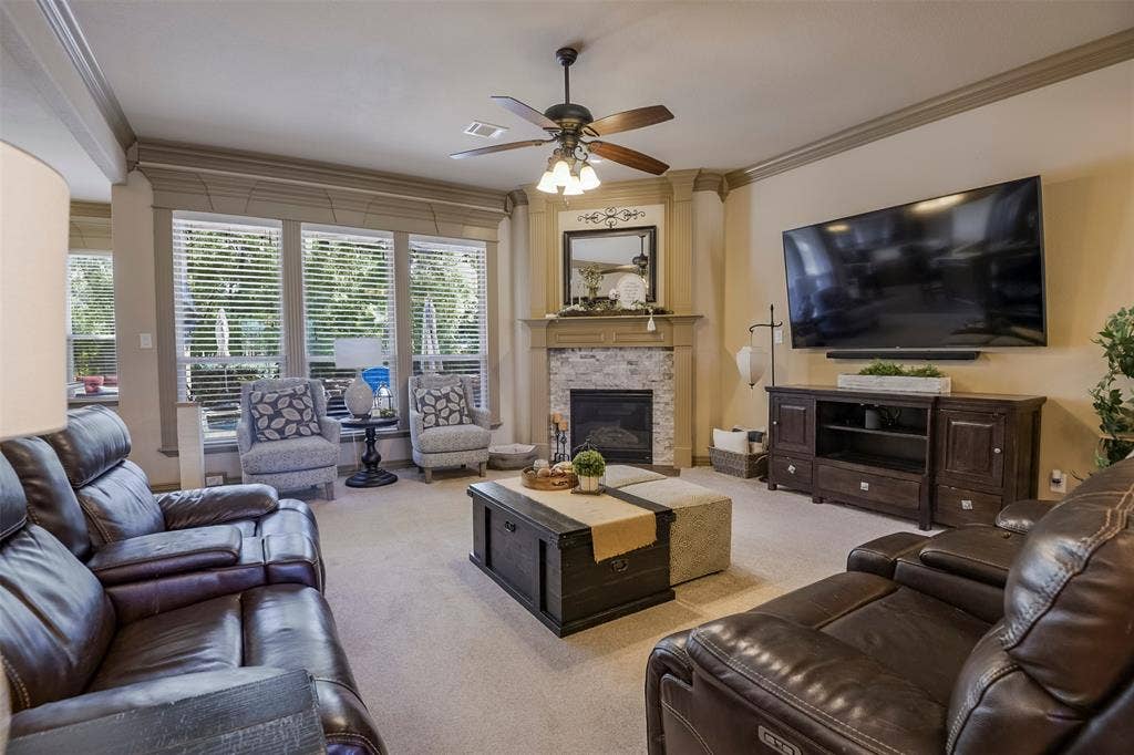 Living area featuring a corner fireplace with a stone surround, a wood mantel, and built-in shelving, view of pool in back and tons of trees.